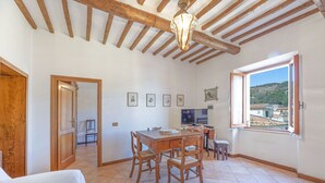A dining area with a wooden table and chairs, a ceiling with exposed beams, and a window with a view of a hillside. - Casa al secco apartment with sea view in the heart of Rio Marina (Rio Marina)