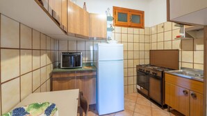 A compact kitchen with a built-in oven, a refrigerator, and a stove. - Casa al secco apartment with sea view in the heart of Rio Marina (Rio Marina)