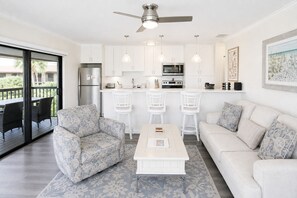 A modern kitchen with white cabinets, a built-in microwave, and a stainless steel refrigerator.