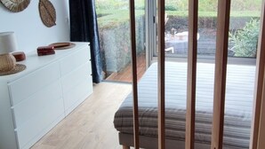 A modern bedroom with a large sliding glass door leading to a balcony, a white dresser, and a bed with a striped duvet. - Lovely Beach, Entre la Plage et la Piscine (Sainte-Maxime)