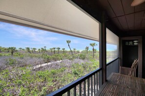 Un balcon offrant une vue sur un paysage côtier, avec des arbres et l’océan.