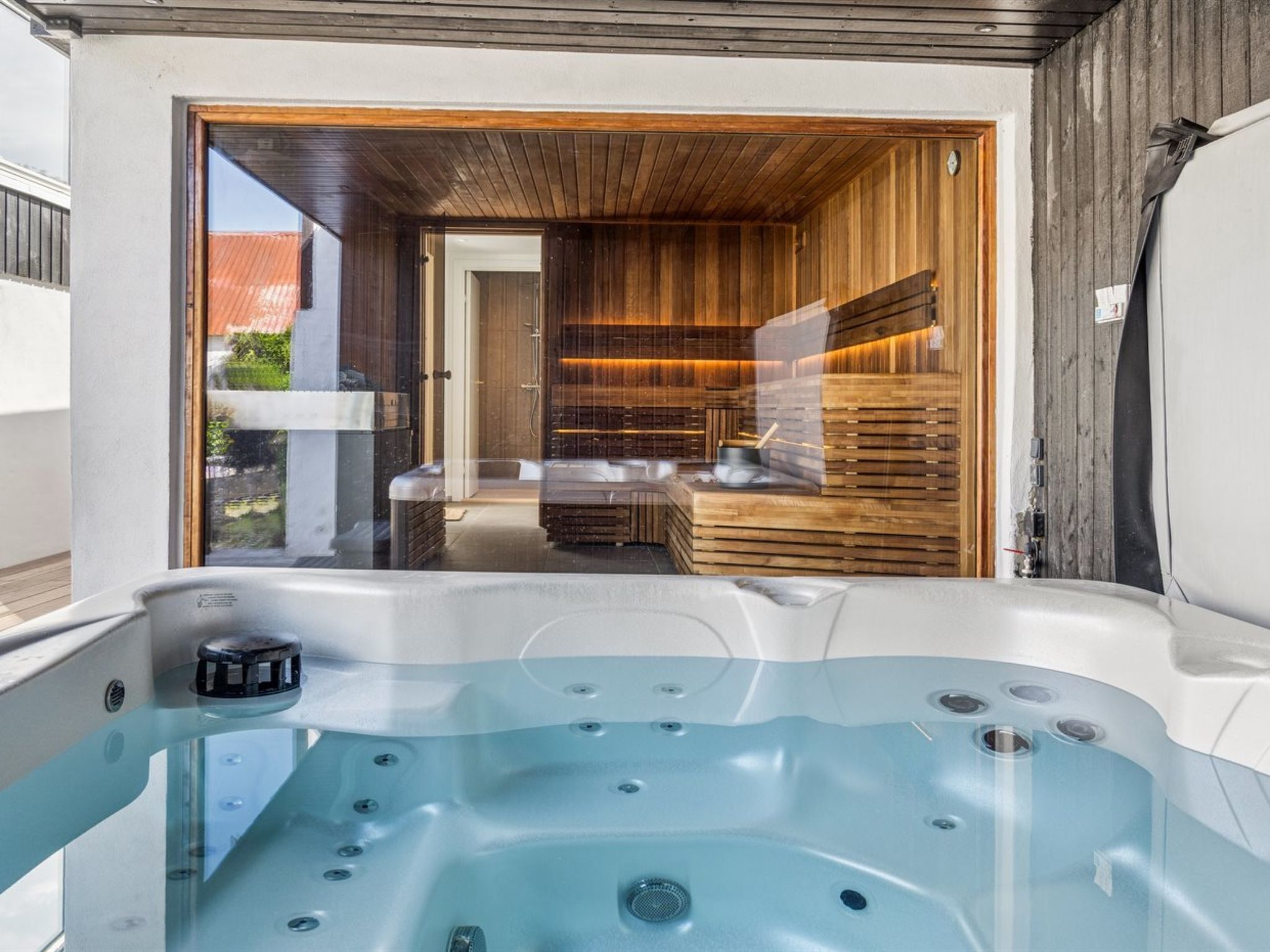 Ein modernes Badezimmer mit einer Glaskabine für eine Hot Tub, Holzvertäfelung und Blick ins Freie.