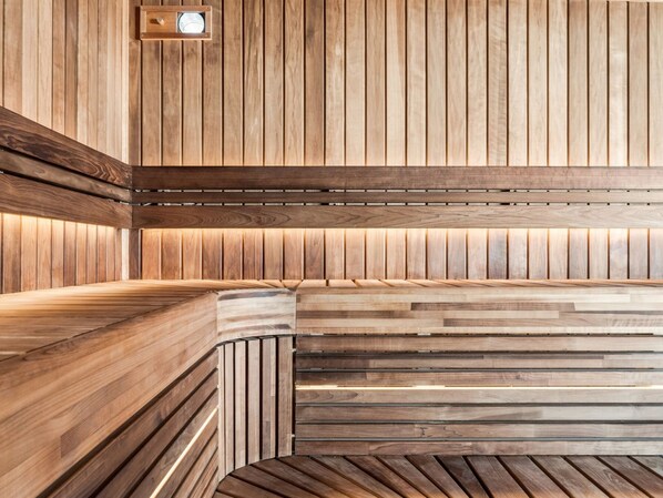 A wooden sauna with a bench and a light fixture.