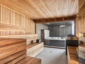A sauna with wooden benches and a glass-enclosed steam room.