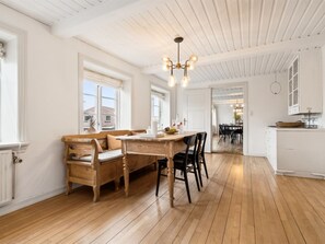 Een ruime keuken met een houten eettafel, een inbouwbank en een hangende lamp.