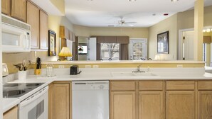 A modern kitchen with wooden cabinets, a microwave, stove, dishwasher, and a large window with a view of trees. - Dog Friendly, Discounted Tee Times, Course Views, Near Hwy 76! (Branson)