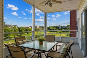 Ein überdachter Balkon mit Glastisch, Korbstühlen und Deckenventilator.