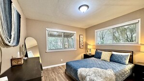 Un dormitorio con cama, escritorio y dos ventanas con persianas.