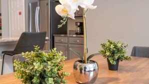 Una mesa de comedor con una orquídea en maceta y otras dos plantas en macetas.