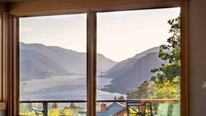 Una stanza con un'ampia finestra che si affaccia su un paesaggio montuoso e un lago.