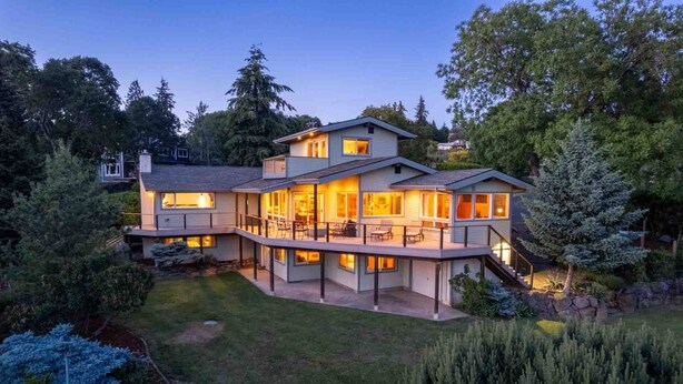 Una casa a più piani con un portico coperto e un giardino curato.