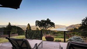Una terrazza con due sedie e un tavolo, che si affaccia su un panorama mozzafiato di montagne e un lago.