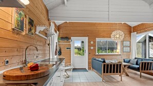 A modern kitchen with wooden walls, a dining area with a sofa, and a large window with a view. - "Oddger" - 250m to the fjord by Interhome (Skjern)