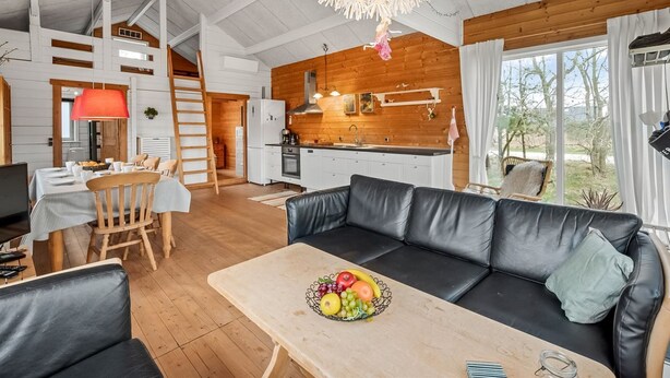 A spacious living area with a dining table, a black leather sofa, and a fruit bowl. - "Oddger" - 250m to the fjord by Interhome (Skjern)