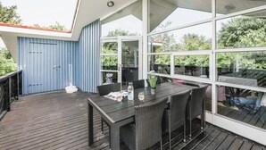 A covered outdoor area with a table and chairs, large windows, and a blue door. - "Ingelis" - 150m to the fjord by Interhome (Tarm)