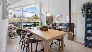 A cozy living room with a wooden table, chairs, a sofa, and a fireplace. - "Ingelis" - 150m to the fjord by Interhome (Tarm)