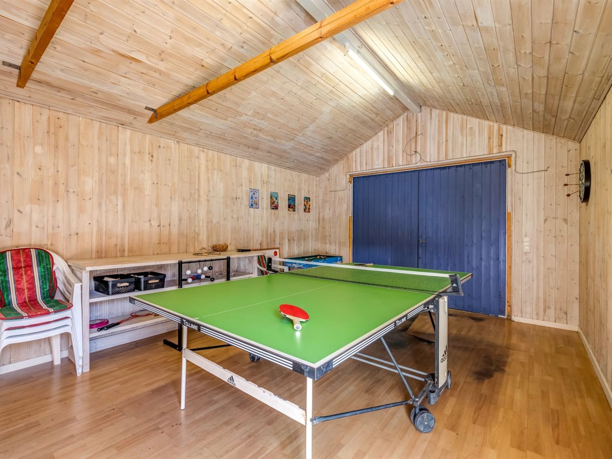 Una sala con pareti in legno e soffitto spiovente, con un tavolo da ping pong.