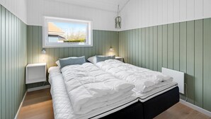 A bedroom with a large bed, two bedside tables, a window with a view, and a hanging plant. - "Ingelis" - 150m to the fjord by Interhome (Tarm)