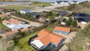 An aerial view of a coastal residential area with houses, a marina, and a large white building with a dark roof. - "Ingelis" - 150m to the fjord by Interhome (Tarm)