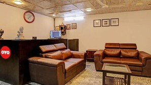 Una habitación con un sofá de cuero marrón, una mesita pequeña y una recepción con un reloj.
