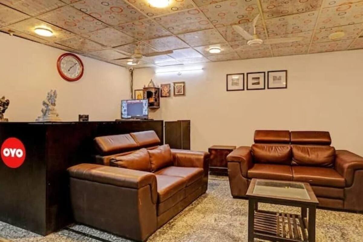 Una habitación con un sofá de cuero marrón, una mesita pequeña y una recepción con un reloj.