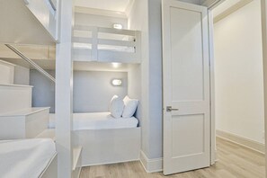 Ein kleines, modernes Schlafzimmer mit Etagenbett, Nachttisch und Tür.