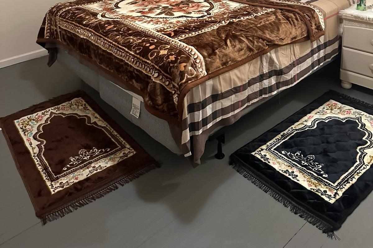 A neatly arranged bedroom with a large bed, a bedside table, and two rugs.