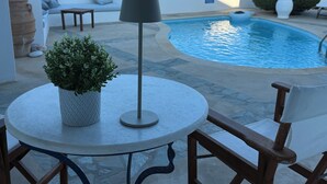 A round table with a potted plant, a floor lamp, and a chair.