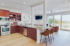 A modern kitchen with a central island, stainless steel appliances, and a large window overlooking a scenic view. - Fantastic Water Views, Pool, Hot Tub, Outdoor Kitchen, Fishing Dock, Waterfront Updated Home, DogsOK (Wilmington)