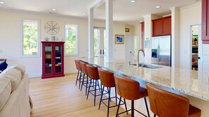 A modern kitchen with a large island, bar stools, and a built-in refrigerator. - Fantastic Water Views, Pool, Hot Tub, Outdoor Kitchen, Fishing Dock, Waterfront Updated Home, DogsOK (Wilmington)