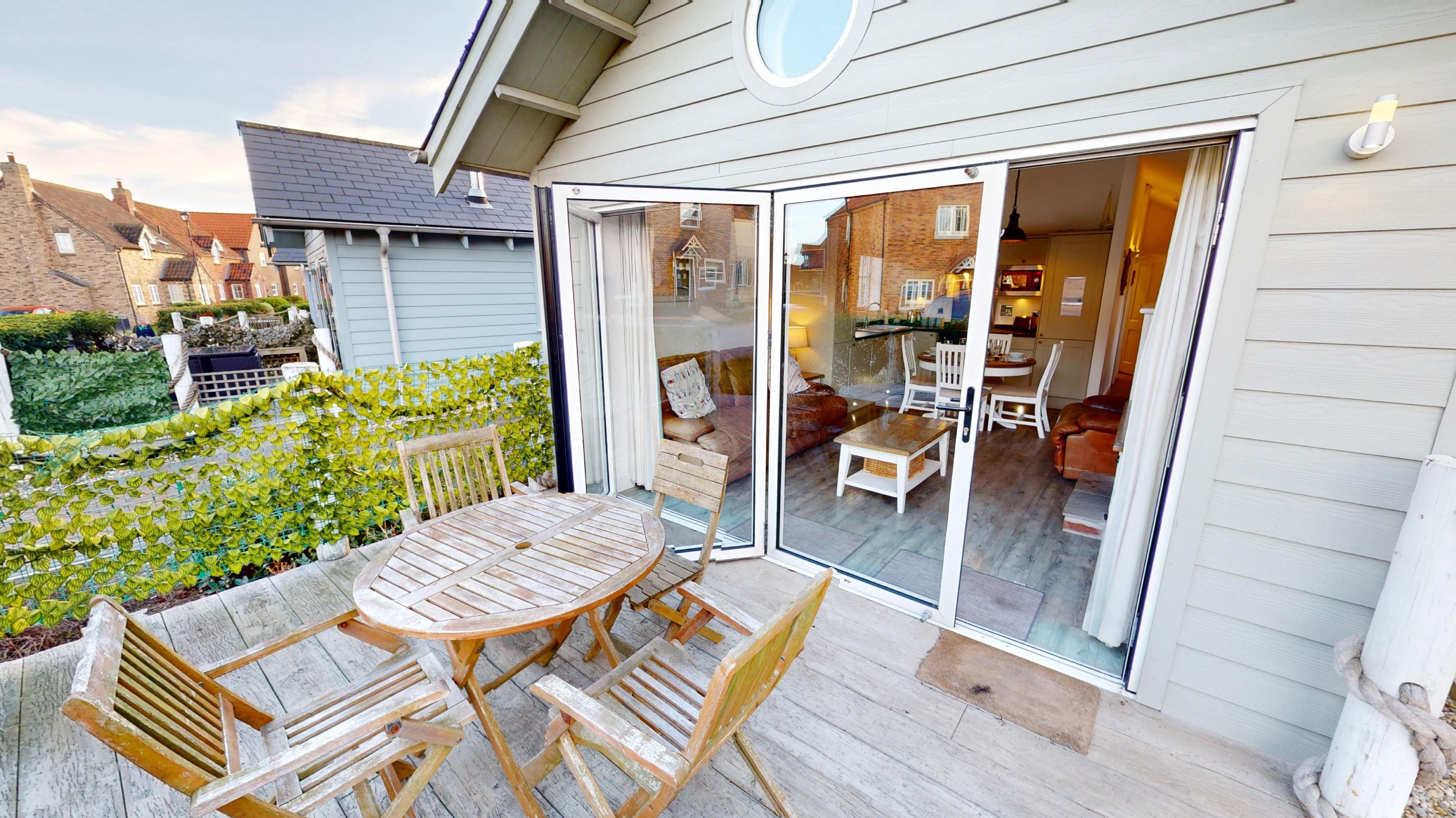 A patio with a table and chairs, a sliding glass door leading to an interior space with a dining area and seating.