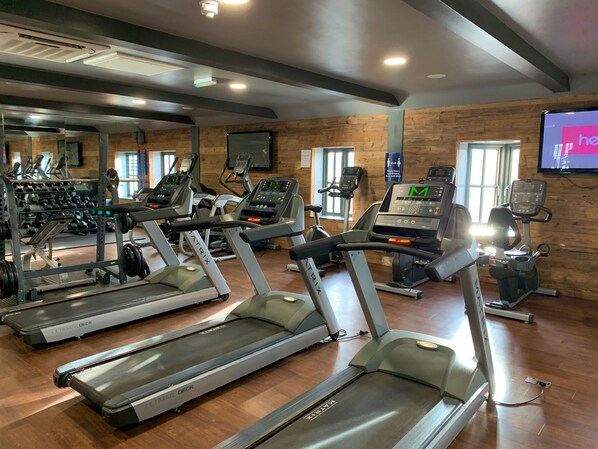 A gym with treadmills, weight machines, and a mirrored wall. - Sophie Beach Hut -  a beach house that sleeps 4 guests  in 2 bedrooms (Filey)