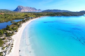 A coastal landscape with a beach, clear blue waters, and a mountain in the background. - Pittulongu Villa near Rocce Beach for 4 (Pittulongu (SS))