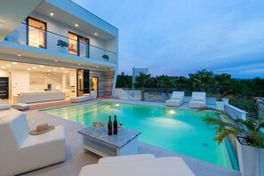 A modern two-story house with a swimming pool, outdoor seating, and a staircase leading to an upper level. - Luxury villa with pool, wellness and sea view (Maslenica)