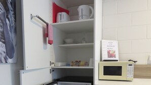 Een kleine keuken met een ingebouwde magnetron, een minibar en een prullenbak.
