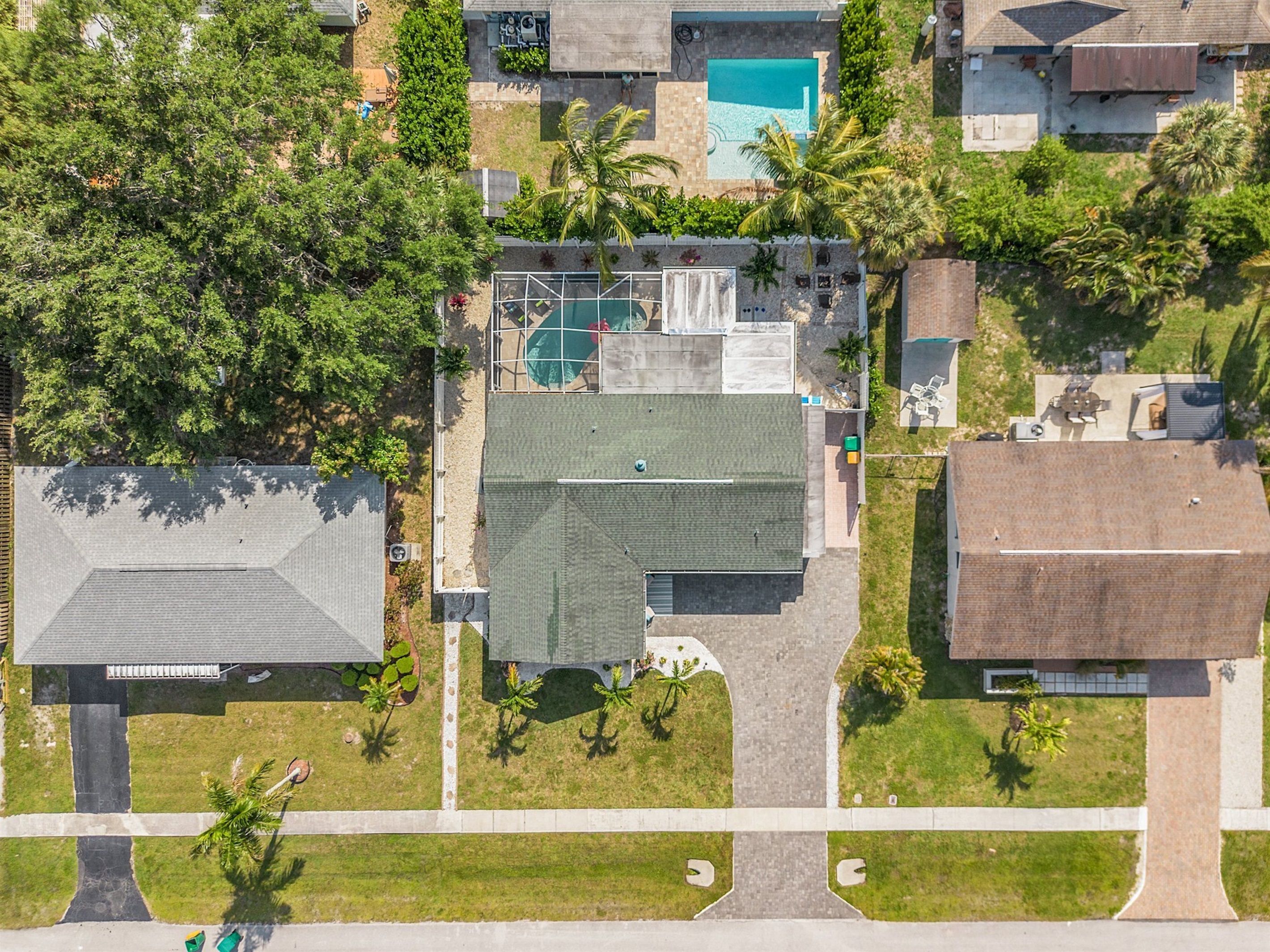 An aerial view of a residential area with a swimming pool, green spaces, and houses.