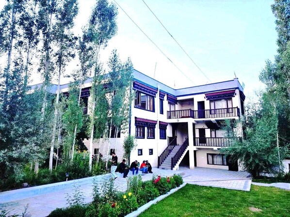 Un edificio de varios pisos con una escalera central, rodeado de follaje y árboles.