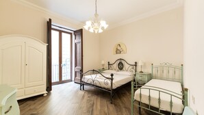 Ein Schlafzimmer mit Holzboden, einem Bett mit Metallgestell, einem Nachttisch, einer Kommode und einer Pendelleuchte.
