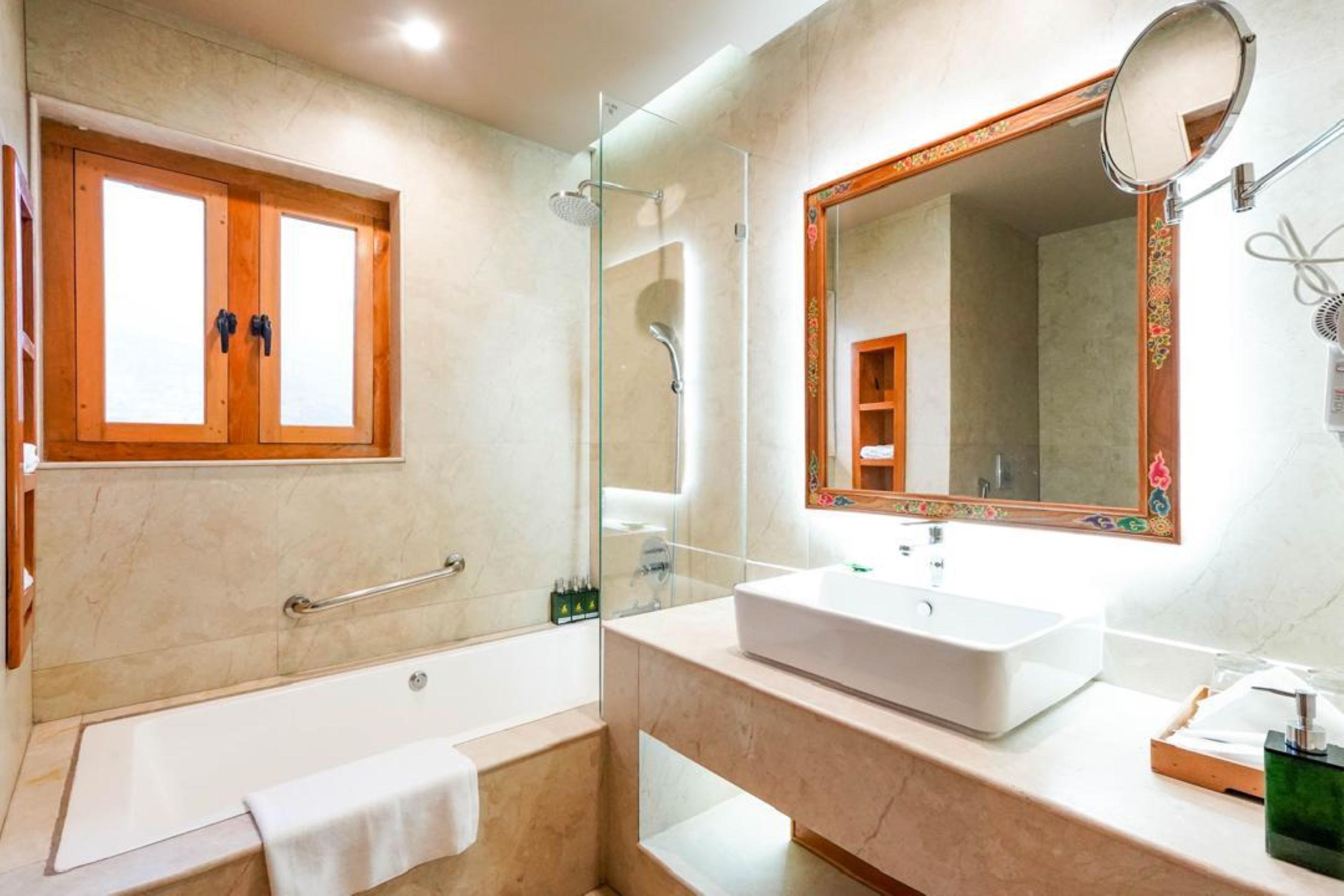 A modern bathroom with a bathtub, a large mirror, and a vanity with a sink.