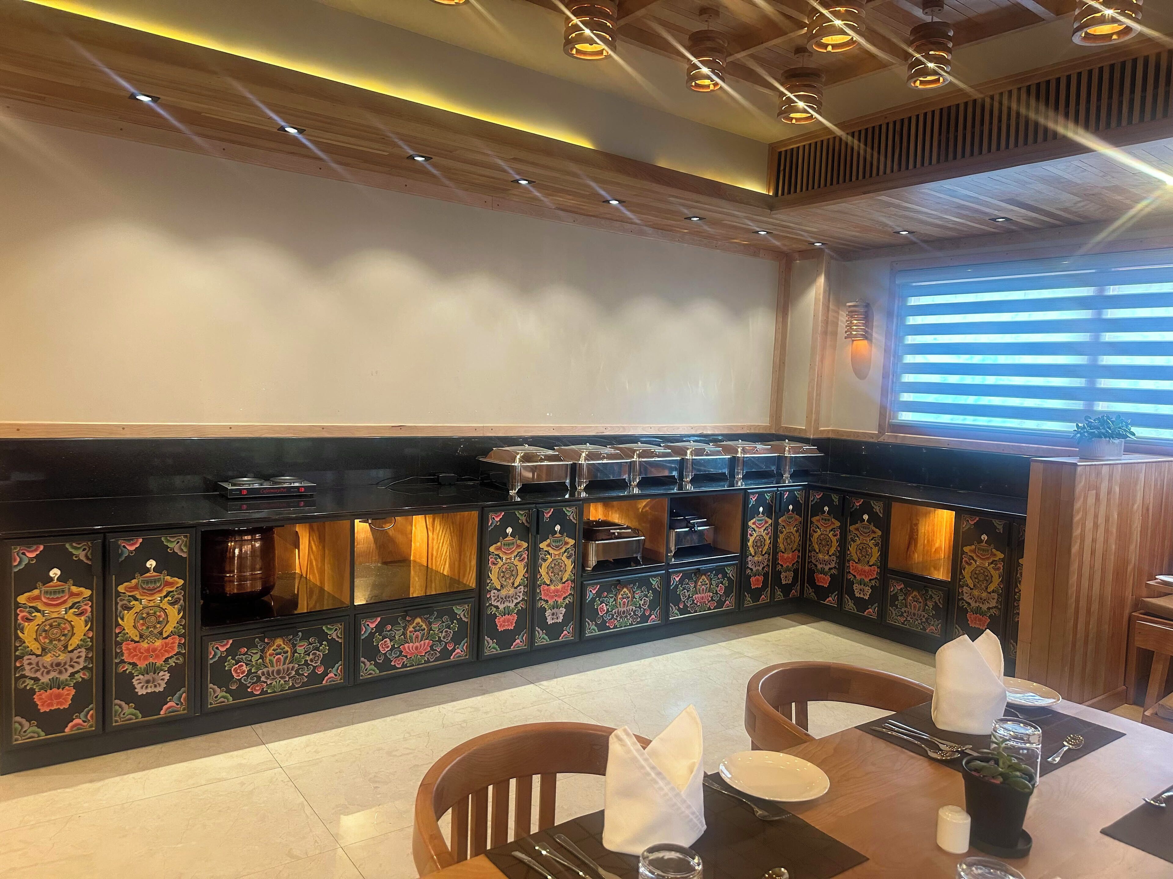 A restaurant with a black counter, decorative panels, and a window with blinds.