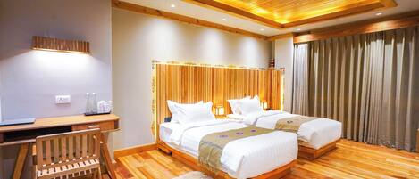 A hotel room with a wooden floor, two beds, a desk, and a chair.