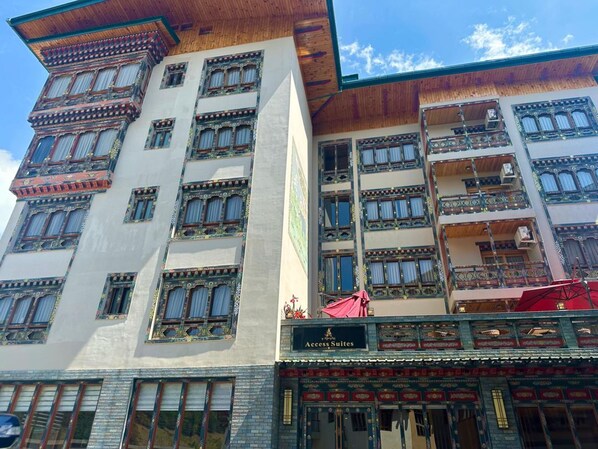 Un hotel de varios pisos con elementos arquitectónicos tradicionales, incluyendo elaboradas molduras de ventanas y balcones.