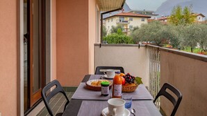 Un balcon avec une table préparée pour le petit-déjeuner, comprenant du pain, des fruits et des boissons.