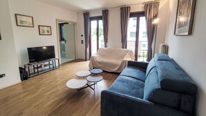 Un salon moderne avec un téléviseur à écran plat, un canapé, un fauteuil et une petite table basse.