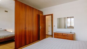A bedroom with a bed, a wooden wardrobe, a dresser, and a mirror. - Nice apartment for 4 guests with WIFI and TV (Pergine Valsugana)