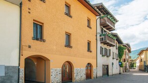 A narrow cobblestone street lined with traditional buildings featuring arched doorways and balconies with hanging plants. - Nice apartment for 4 guests with WIFI and TV (Pergine Valsugana)