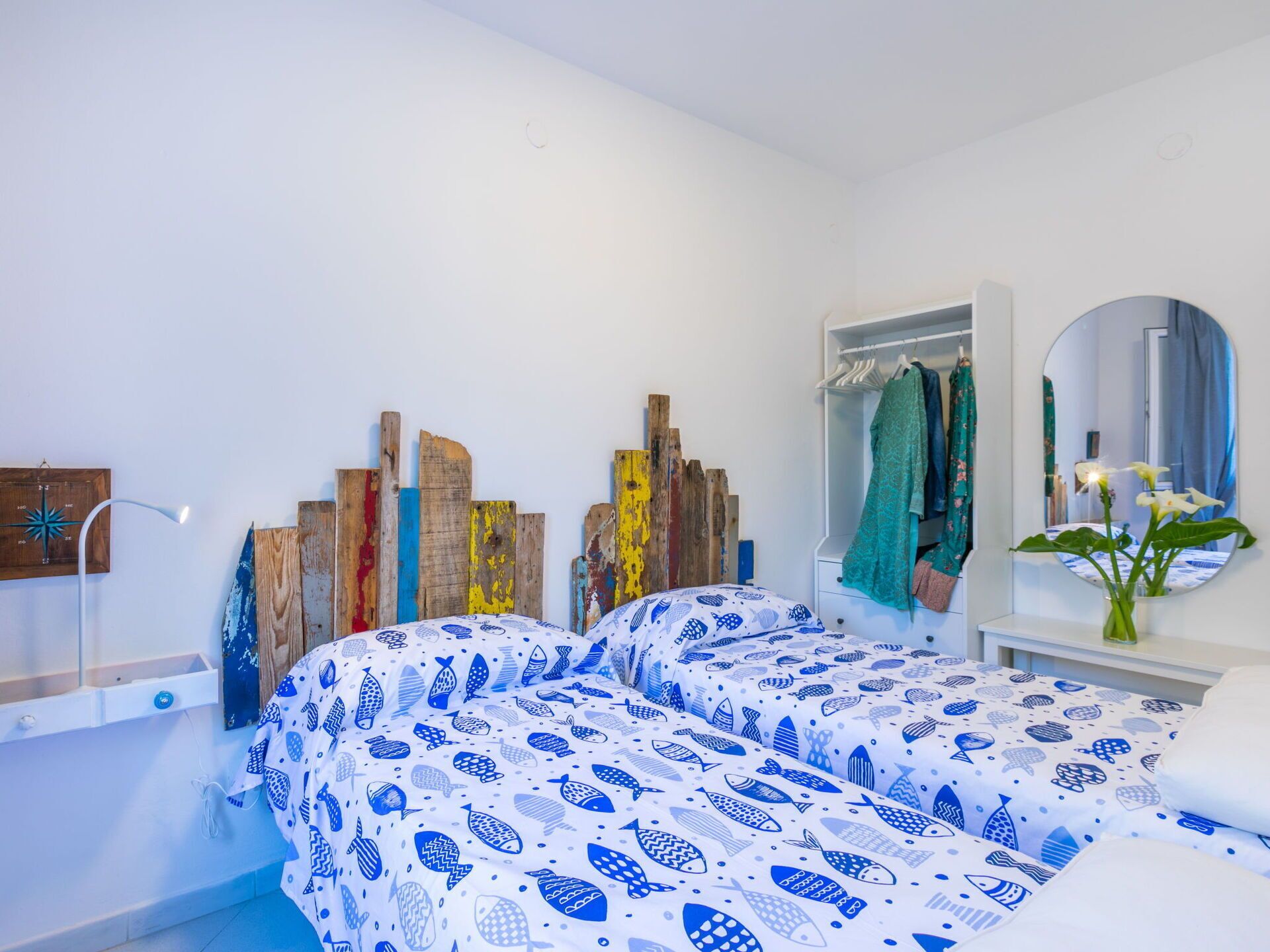Ein Schlafzimmer mit Bett, Kleiderschrank, Spiegel und einer Wandleuchte.
