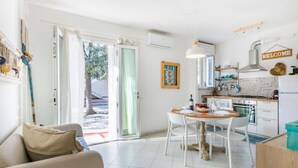 A bright, open-plan living and dining area with a sofa, dining table, and kitchen. - Lovely apartment for 4 people with WIFI, A/C, TV, balcony and pets allowed (Cecina)