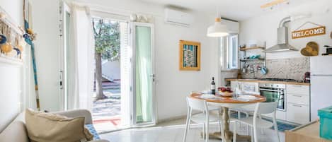A bright, open-plan living and dining area with a sofa, dining table, and kitchen.