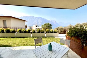 A patio with a table and chairs, a vase, and a view of mountains. - Large, bright and modern flat with an incredible view on lake Garda in Malcesine (Malcesine)